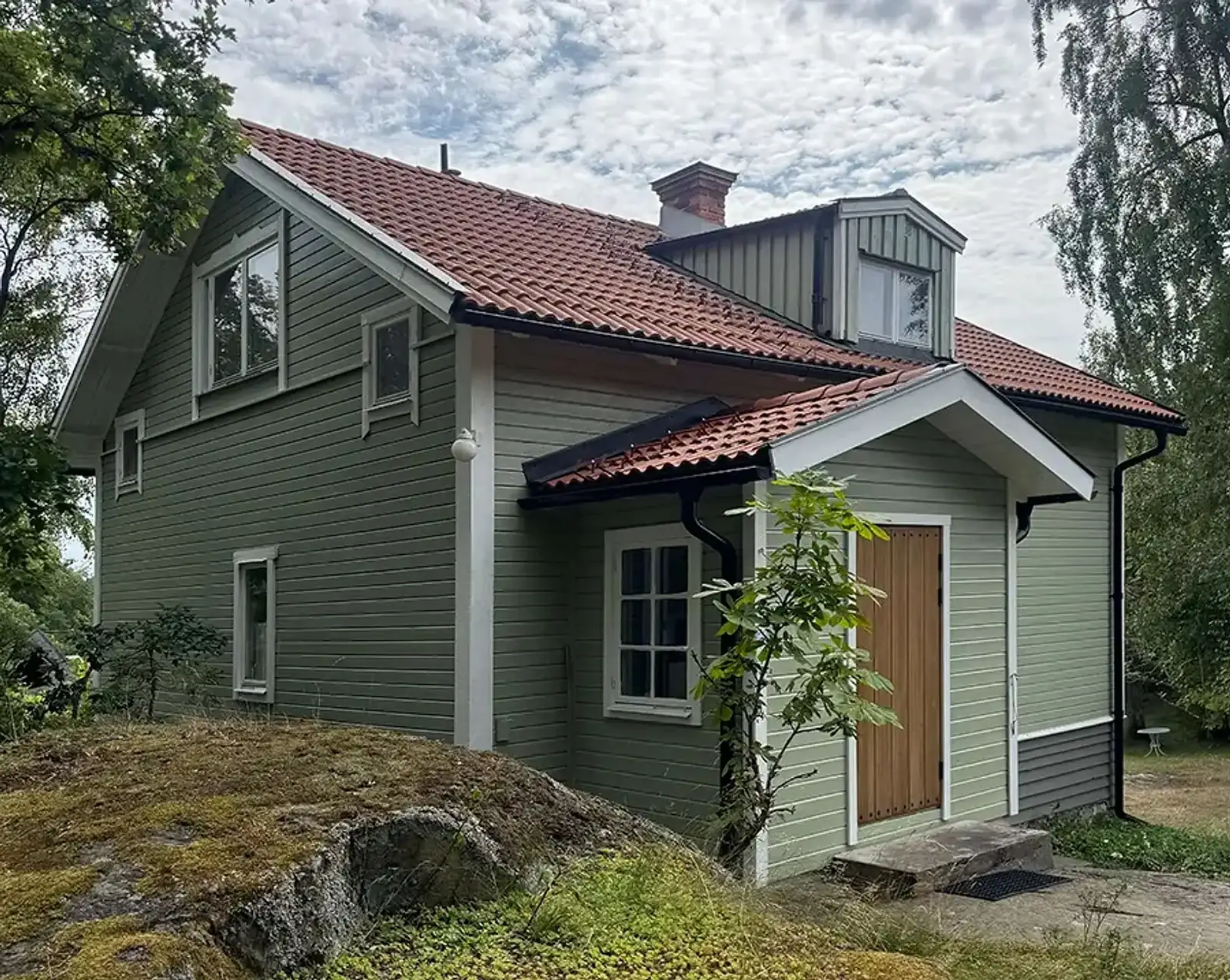 Grönmålat trähus med vita fönster och snickerier